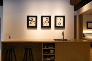 a kitchen with three pictures on the wall and three stools at Hagi Kannuki 168 -萩 閂いろは- in Hagi