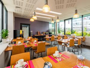 un restaurante con mesas y sillas de madera y ventanas en Lagrange Apart’Hotel Paris-Boulogne, en Boulogne-Billancourt