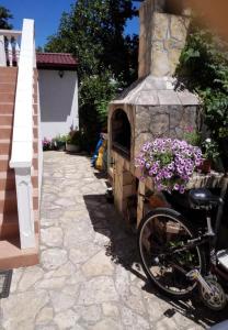 ein Fahrrad neben einem Steinofen mit Blumen geparkt in der Unterkunft Apartments Dobri - 500m from beach in Batalaži