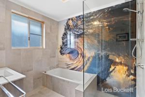 uma casa de banho com uma banheira e um chuveiro em vidro. em Sea Whisper em Lennox Head