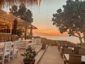a restaurant with white tables and chairs and the ocean at High Life Bungalow in Haad Yao