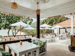 a restaurant with white tables and white chairs and umbrellas at High Life Bungalow in Haad Yao