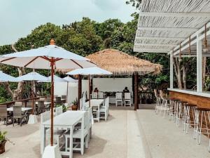 a patio with white tables and chairs and umbrellas at High Life Bungalow in Haad Yao