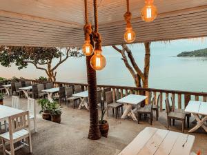 a patio with tables and chairs and a view of the water at High Life Bungalow in Haad Yao