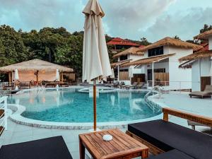a pool with an umbrella and tables and chairs at High Life Bungalow in Haad Yao