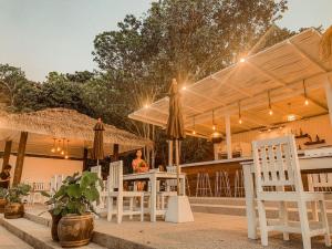 a patio with white chairs and umbrellas at High Life Bungalow in Haad Yao
