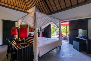 a bedroom with a canopy bed and a television at Rouge - Private Villa Passion in Ubud