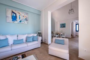 een woonkamer met een witte bank en blauwe kussens bij Santorini Mystique Garden Villa in Kamari