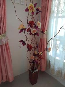 a bouquet of flowers in a vase next to a window at Bukittinggi Homestay 2 in Bukittinggi