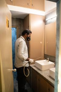 a man wearing a mask standing in front of a bathroom sink at Hotel Beebiz Guindy in Chennai
