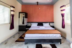 a bedroom with a bed with a red wall at Krishna Homestay Hampi in Hampi