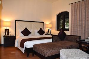 a bedroom with a large bed and a couch at Ramada Plaza by Wyndham Karachi Airport Hotel in Karachi