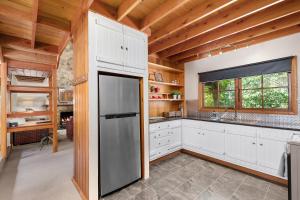 uma cozinha com armários brancos e um frigorífico de aço inoxidável em Stonehenge Retreat em Ballarat