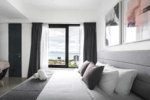 1 dormitorio con cama blanca y ventana grande en Tropicana 218 Macalister by Simply Penang en George Town