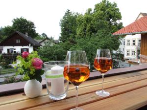 trois verres de vin assis sur un livre en bois dans l'établissement Haus Schaffler, à Kochel am See