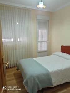 een slaapkamer met een wit bed en een raam bij Apartamentos Maranata Foz in Foz
