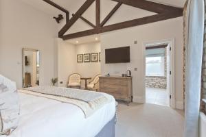Schlafzimmer mit einem Bett, einem Schreibtisch und einem TV in der Unterkunft Tithe Barn - Self Check In Hotel in Cockermouth