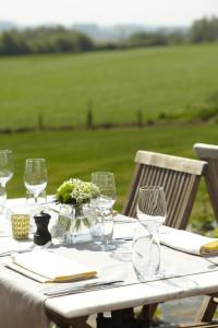 a table with wine glasses and a field in the background at vakantieverblijf Pand19 in Geraardsbergen