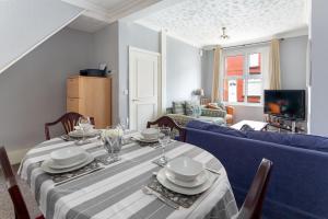 44 Stonehill Street في ليفربول: غرفة طعام مع طاولة وأريكة زرقاء