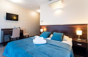 a bedroom with a blue bed with a desk and a computer at Villa nad Zalewem in Dziwnówek