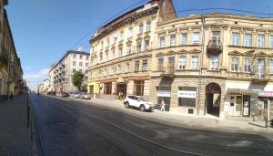 Family Stay in Lviv (2 Rooms + Kitchen) في Kulʼparkuv: سيارة بيضاء متوقفة أمام مبنى