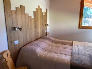 a bedroom with a bed with a wooden headboard at Eco Chalet Nonno Silvano in Bedollo