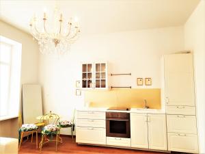 una cocina con armarios blancos y una lámpara de araña en Sisi-Schloss Rudolfsvilla - Appartement Elisabeth, en Reichenau