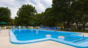 a large swimming pool with blue chairs and chairs at Ocean Park Inn Cape Cod in Eastham