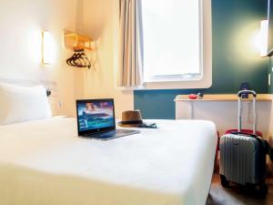 a laptop computer sitting on top of a bed with a suitcase at ibis budget Sao Caetano in São Caetano do Sul