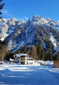 a house in the snow in front of a mountain at Hotel Ristorante Genzianella in Madonna di Campiglio