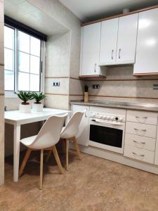 a kitchen with white cabinets and a table and chairs at Apartamento Plaza Mayor Trujillo in Trujillo