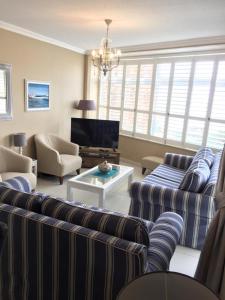 sala de estar con sofás a rayas y TV en Unit 62 Sealodge Umhlanga Beach en Durban