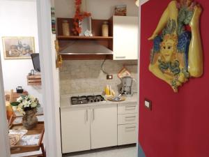 a kitchen with white cabinets and a red wall at La Casa di Pina in Modica