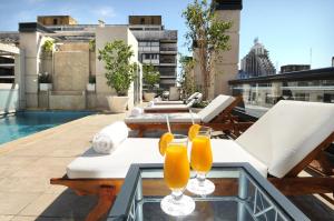 two glasses of orange juice on a glass table on a balcony at Windsor Hotel in Córdoba
