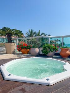 un jacuzzi sur une terrasse avec des plantes en pot dans l'établissement Pousada Gaúcha, à Bombinhas