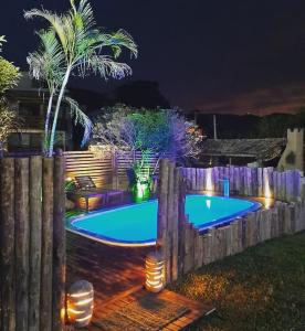 a backyard with a swimming pool at night at Quinta do Urutau in Praia do Rosa