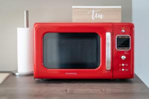 a red microwave sitting on top of a table at Les Cerisiers - Duplex de Standing au Centre de Namur in Namur +22 photos