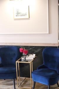 2 chaises bleues et une table avec un vase de fleurs dans l'établissement Hotel POD RÓŻAMI, à Jedlnia-Letnisko