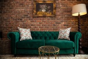 a green couch in a room with a brick wall at Tarry-Stone Cottages in Dullstroom