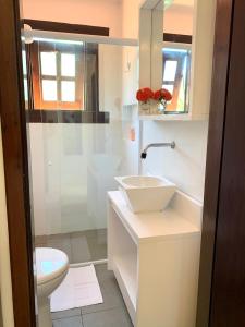 uma casa de banho branca com um lavatório e um WC em Loft Jeri em Jericoacoara