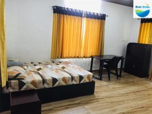 a bedroom with a bed and a table and yellow curtains at River Arena Holidays in Vagamon