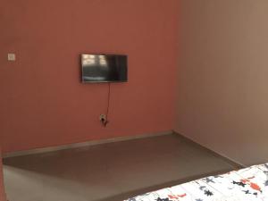 a bedroom with a tv on the wall and a bed at Elstine’s in Lagos