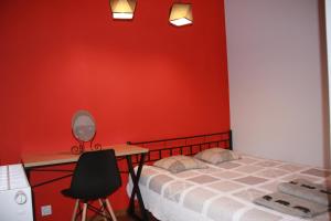 a bedroom with a red wall and a bed and a desk at Niko Apartments 1 in Krakow