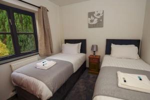2 camas individuales en una habitación con ventana en Conwy Valley Hotel Cottages, en Conwy