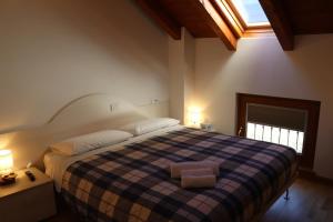 a bedroom with a large bed with a plaid blanket at A DUE PASSI affittacamere - Ovaro in Ovaro