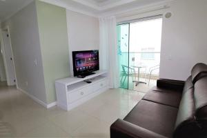 sala de estar con sofá y TV de pantalla plana en 1053 - Praia de Bombinhas locação de temporada - Residencial Egídio Pinheiro Apto 302 B, en Bombinhas