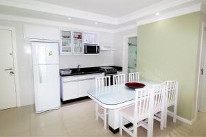 cocina con mesa y nevera blanca en 1053 - Praia de Bombinhas locação de temporada - Residencial Egídio Pinheiro Apto 302 B, en Bombinhas
