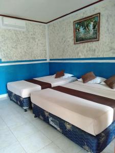 3 camas en una habitación con paredes azules en Cozy Alfia Inn, en Gili Trawangan