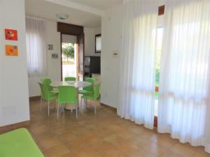 jadalnia ze stołem i zielonymi krzesłami w obiekcie Villa Agavi 3 w Bibione
