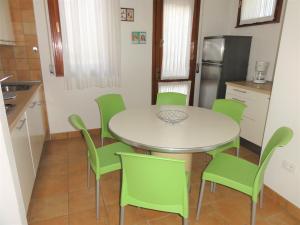 una cucina con tavolo bianco e sedie verdi di Villa Agavi 3 a Bibione